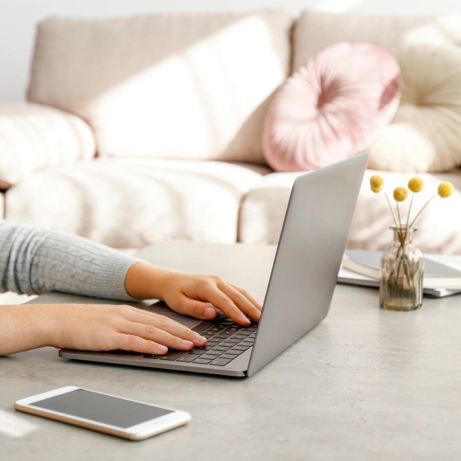 Close-up of a woman’s hands typing on a laptop, exploring pain reprocessing therapy for chronic pain relief