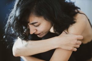 women with arms crossed and distressed expression suffering from chronic pain