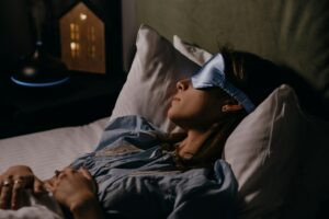 Woman sleeping with an eye mask at night—illustrating restful sleep after nightmare therapy treatment.