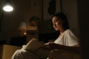 Person reading quietly under a warm lamp before bed, illustrating sleep restriction therapy and sleep consolidation for depression treatment.