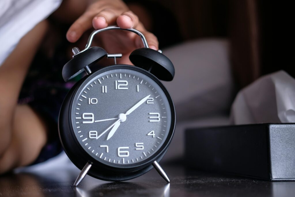 Alarm clock being turned off in the morning, illustrating daylight saving time and anxiety and time change sleep disruption