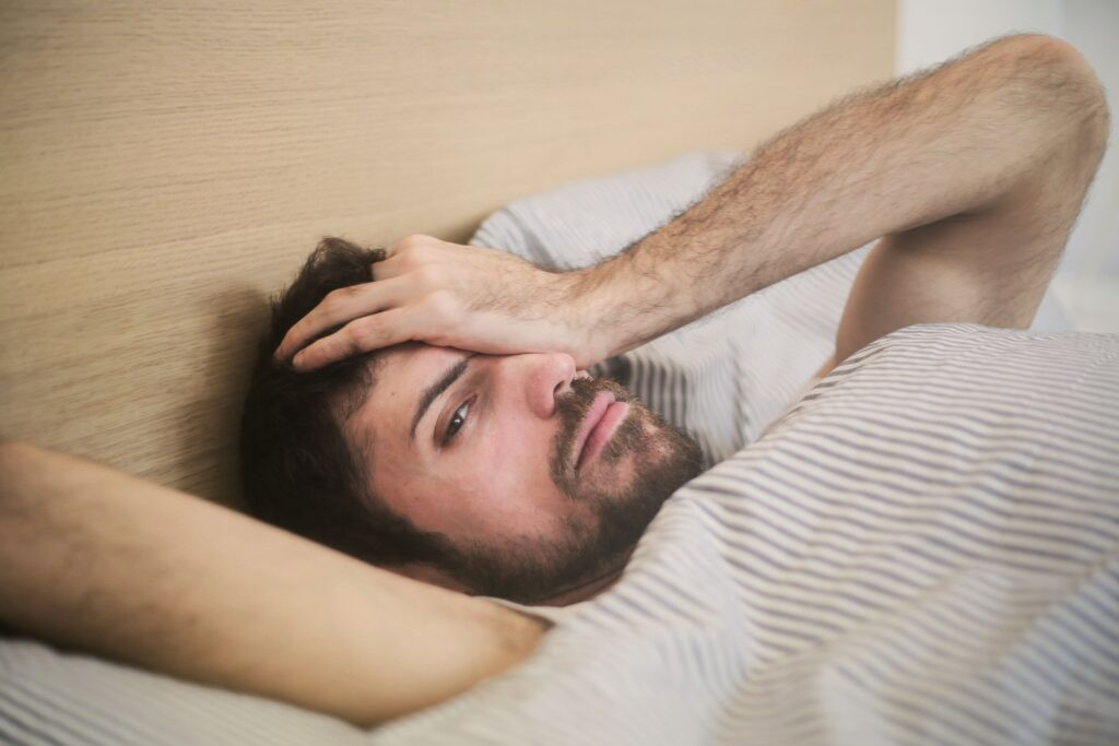 A man waking up tired after 8 hours of sleep.